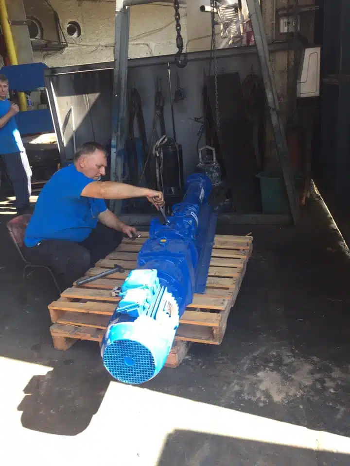 תיקון על ידי עובד בסליל המנוע של משאבה תעשייתית ארוכת ציר המונעת על ידי מנוע חשמלי